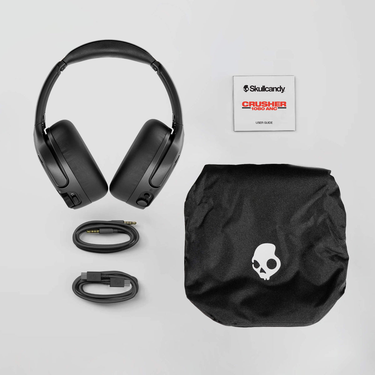 Black headphones with accessories and Skullcandy logo on a light gray background | Primer